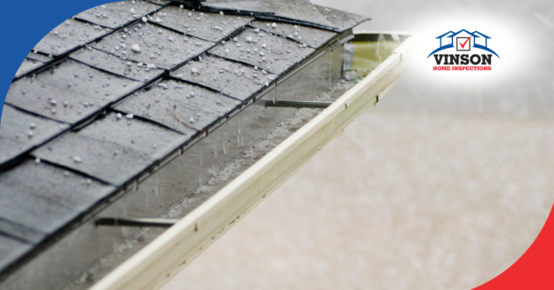Hailstones on asphalt shingle roof with water runoff into gutters, potential damage risk