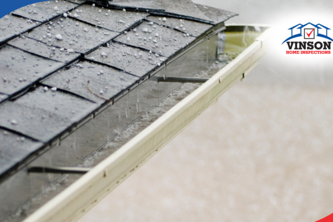 Hailstones on asphalt shingle roof with water runoff into gutters, potential damage risk