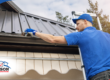 Worker cleaning debris from a home’s gutter.